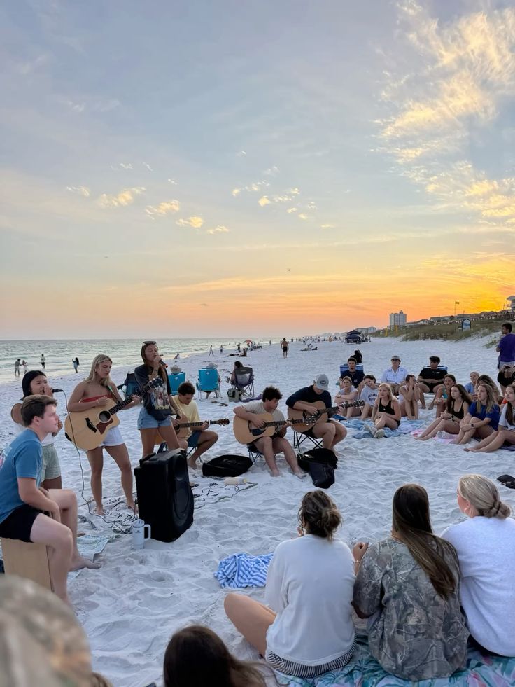 Jóvenes reunidos con guitarras en la playa al atardecer